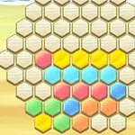 Barevné hexagonální dílky uspořádané v tvaru plástve na písčitém pozadí