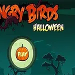 Menu s nápisem v oranžových a žlutých tónech s motivem Halloweenu a tlačítkem Play ve tvaru dýně na tmavém pozadí se siluetami stromů