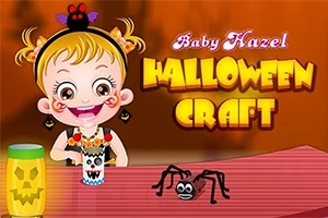 Dítě s úsměvem sedí u stolu s dekoracemi na Halloween, vedle se nachází papírový pavouk a svítilna s motivem dýně