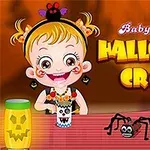 Dítě s úsměvem sedí u stolu s dekoracemi na Halloween, vedle se nachází papírový pavouk a svítilna s motivem dýně