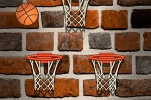 Basketbalový míč a tři basketbalové koše na cihlové zdi