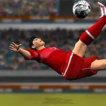 Fotbalista provádí nůžky na hřišti ve stadiónu, oblečený v červeném dresu, zatímco diváci sledují v pozadí