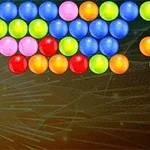 Barevné kuličky uspořádané ve vzoru na tmavém pozadí