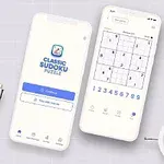 Dva mobilní telefony s aplikací pro řešení sudoku, keramická figurka sovy a rostlina na bílém pozadí