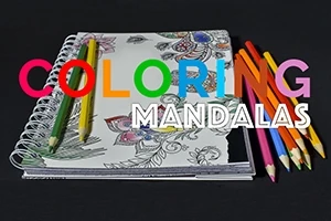 Blok s mandalami, barevné pastelky a nápis COLORING MANDALAS