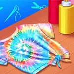 Barevné tričko s batikovaným vzorem spirály leží na stole vedle tří lahviček s barvami na textil