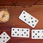 Kompas a několik bílých domino kostek s černými tečkami na hnědém pozadí
