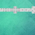 Domino kostky uspořádané do tvaru písmene L na zeleném pozadí