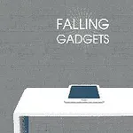Tablet ležící na bílém stole před šedou cihlovou zdí s nápisem Falling Gadgets