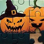 Dvě dýně s vyřezanými obličeji, jedna s čarodějnickým kloboukem, ve formě puzzle na dřevěném podkladu