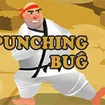 Postava v bílém kimonu s červenou čelenkou stojí na písčitém povrchu s nápisem Punching Bug přes její tělo