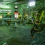 Roboti sedící u stolů v retro-futuristické kavárně s neonovým nápisem a nápojovým barem