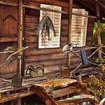 Dřevěná chata s verandou, zavěšenými předměty a okolní vegetací