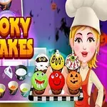 Kuchařka v čepici drží podnos s různobarevnými strašidelnými cupcakes, nápis Spooky Cupcakes a fialové pozadí s kuchyňskými scénami