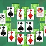 Karty rozložené do kruhu s různými symboly, jako jsou srdce, piky, káry a kříže, na zeleném pozadí
