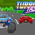 Modré auto Bigfoot a červené sportovní auto na silnici s logem Turbo Tastic v pozadí